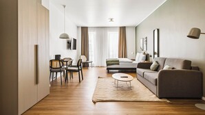 A modern living room with a sofa, coffee table, and dining area. - Limehome Bochum Kortumstr. (Bochum)
