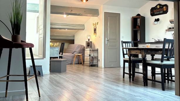 A spacious living area with a wooden floor, a dining table with chairs, a sofa, and a small side table with a lamp. - Cosy and relaxing atmosphere in St Zacharie, in the heart of the village. (Unknown)