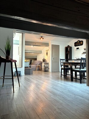 A spacious living area with a wooden floor, a dining table with chairs, a sofa, and a small side table with a lamp. - Cosy and relaxing atmosphere in St Zacharie, in the heart of the village. (Unknown)