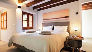 Une chambre à coucher avec un grand lit, une table de chevet, une table ronde sur laquelle se trouve un bol, et un tableau accroché au mur.