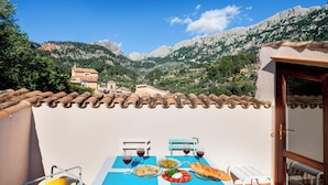 Une terrasse avec une table dressée pour un repas, des chaises et une vue sur les montagnes.