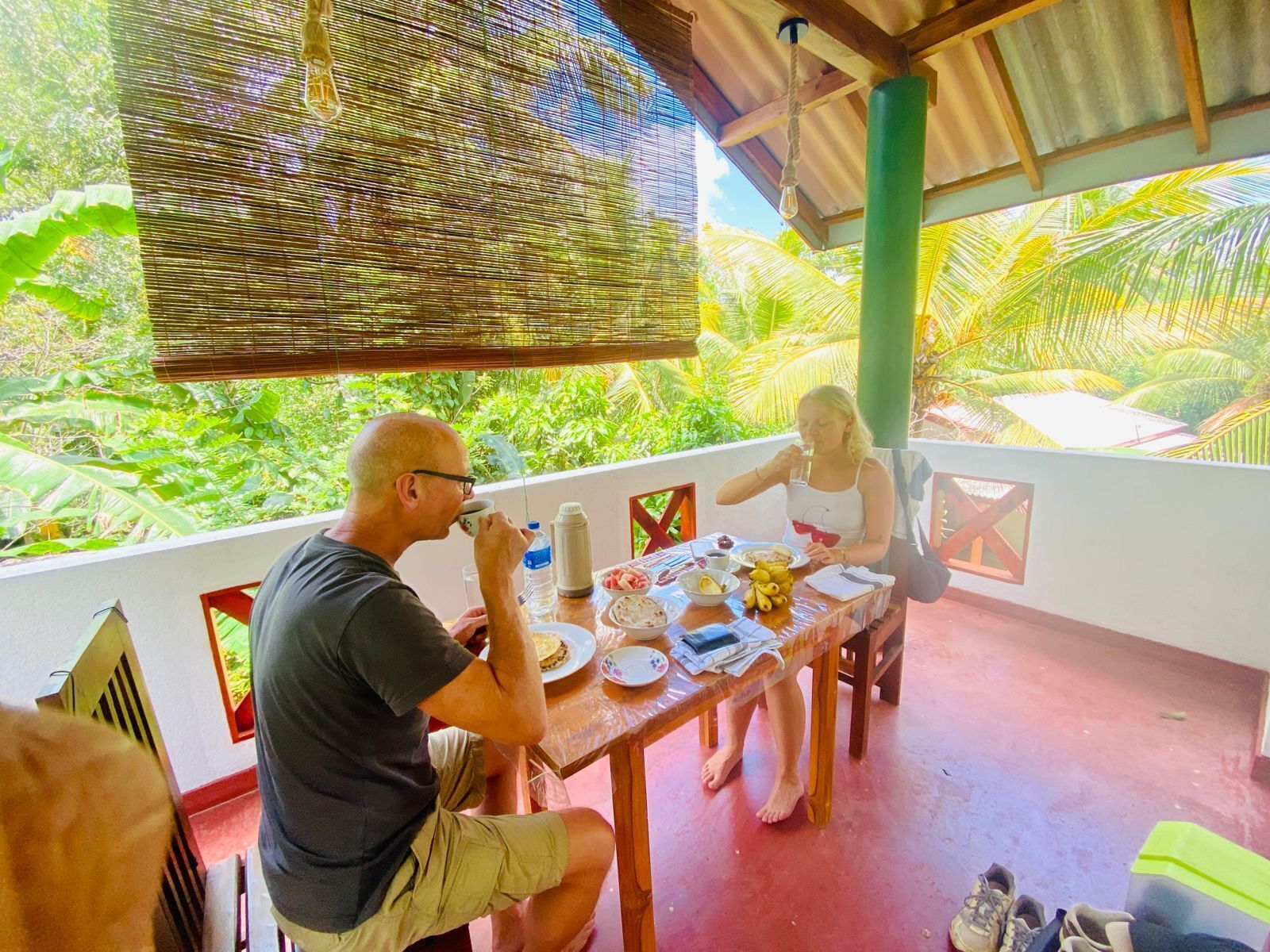 An outdoor dining area with a table set for two, surrounded by lush greenery.