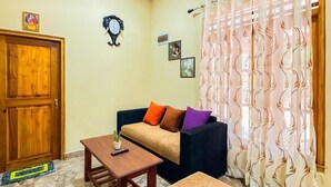 Una sala de estar con sofá, otoman, mesa de centro y una puerta.