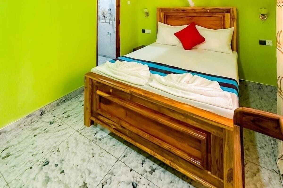 A room with a bed, a wooden headboard, a mosquito net, and a tiled floor.