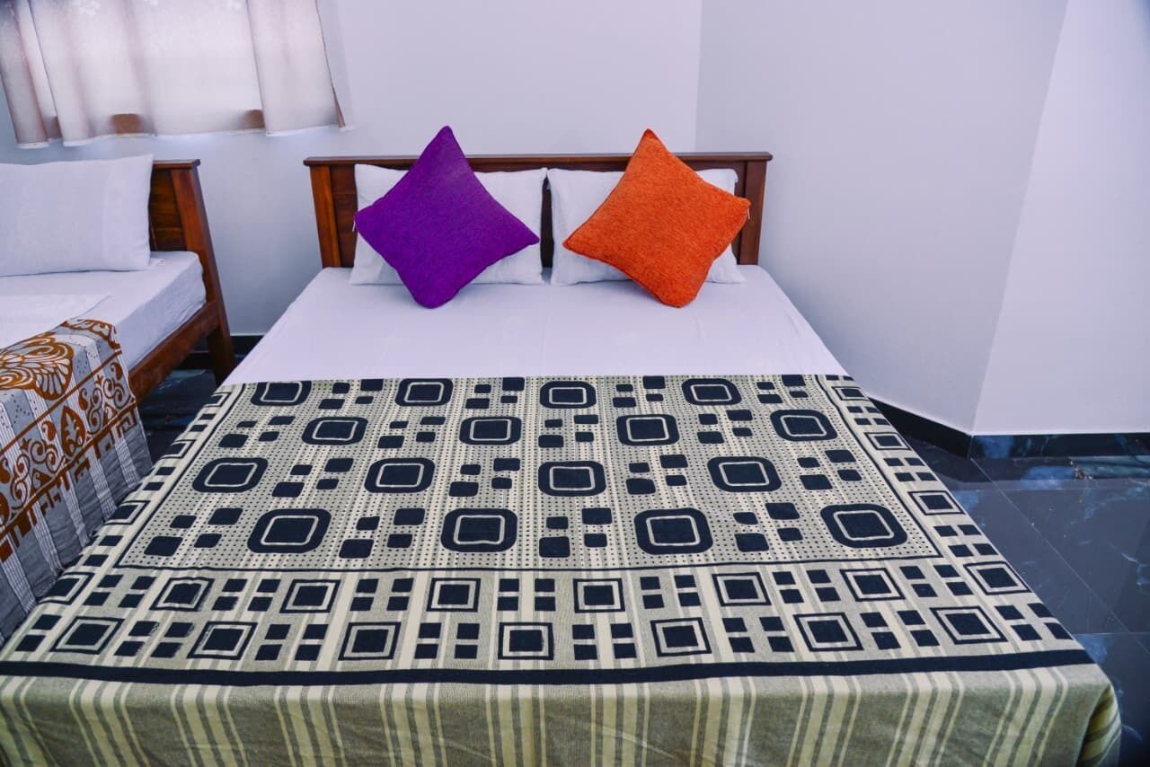 A bed with a patterned bedspread, two pillows, and a wooden headboard.
