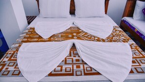Una cama con una colcha estampada y toallas blancas dispuestas en forma de corazón.