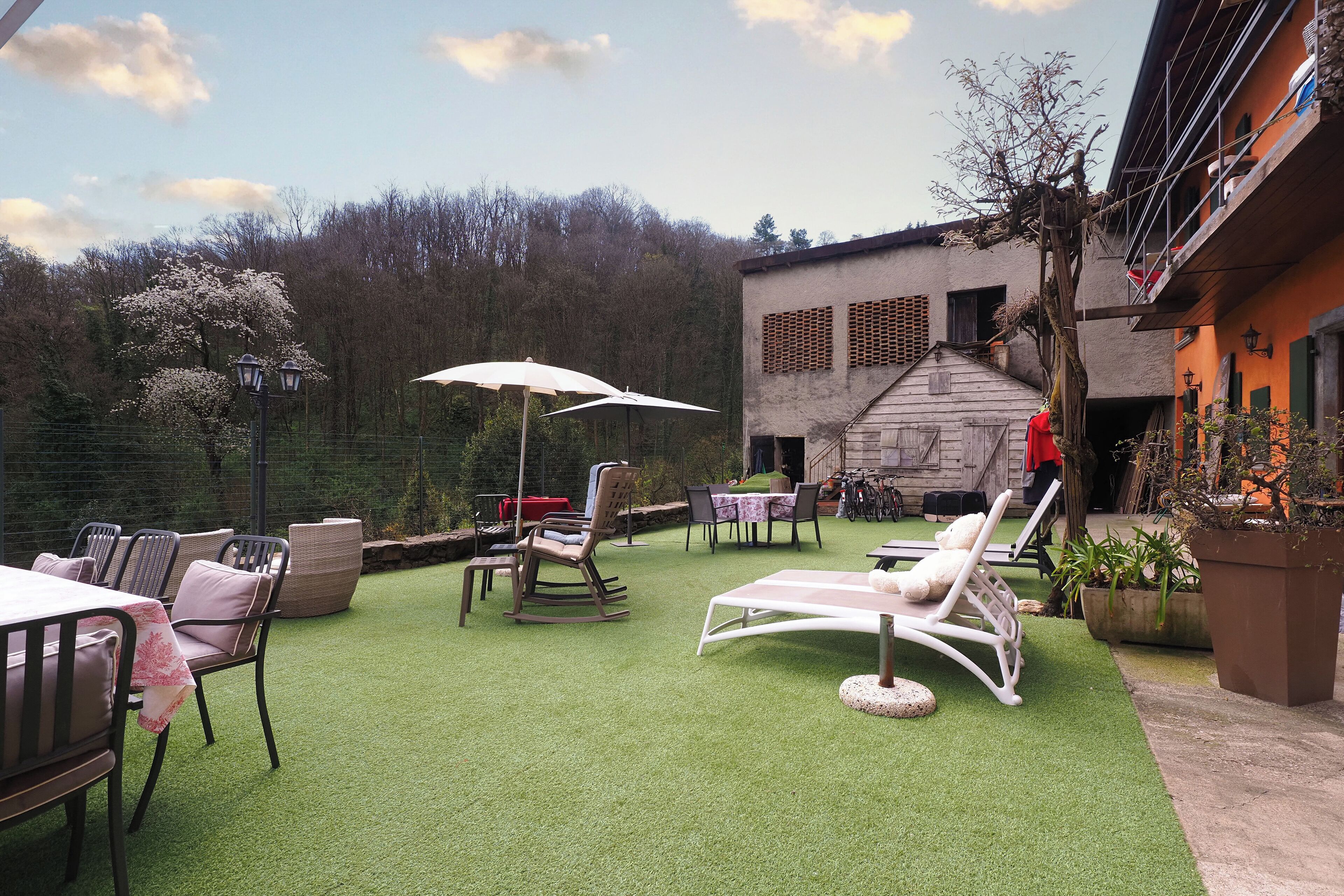 An outdoor patio with artificial grass, seating, and a table with an umbrella.