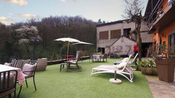 An outdoor patio with artificial grass, seating, and a table with an umbrella.