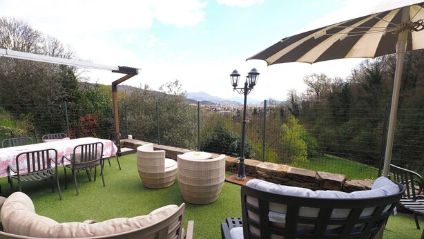 An outdoor patio with a table and chairs, a wicker sofa, and a large umbrella. - .\tGreen in the city exists: discover it at the Hedgehog Mansion with your furry..... (Bergamo)