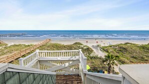 A beach view with a wooden staircase leading down to the shore, a pier in the distance, and a clear sky. - Serenity is Yours! Oceanfront Pool,SP3 (North Myrtle Beach)