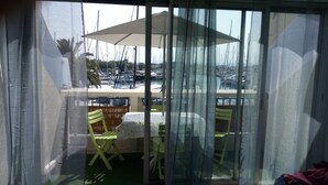 A balcony with a table and chairs, overlooking a marina with boats. - Charming studio in enjoyable La Grande-Motte with WiFi (La Grande-Motte)