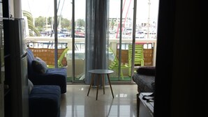 A spacious living area with a large sliding glass door leading to a balcony, a small round table, and a sofa. - Charming studio in enjoyable La Grande-Motte with WiFi (La Grande-Motte)