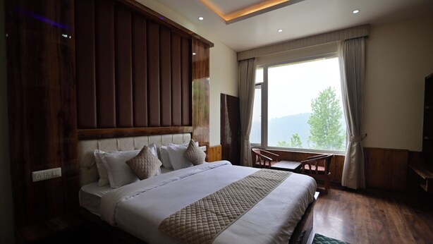 Un dormitorio con una cama grande, cabecera de madera, un escritorio y vistas al exterior.