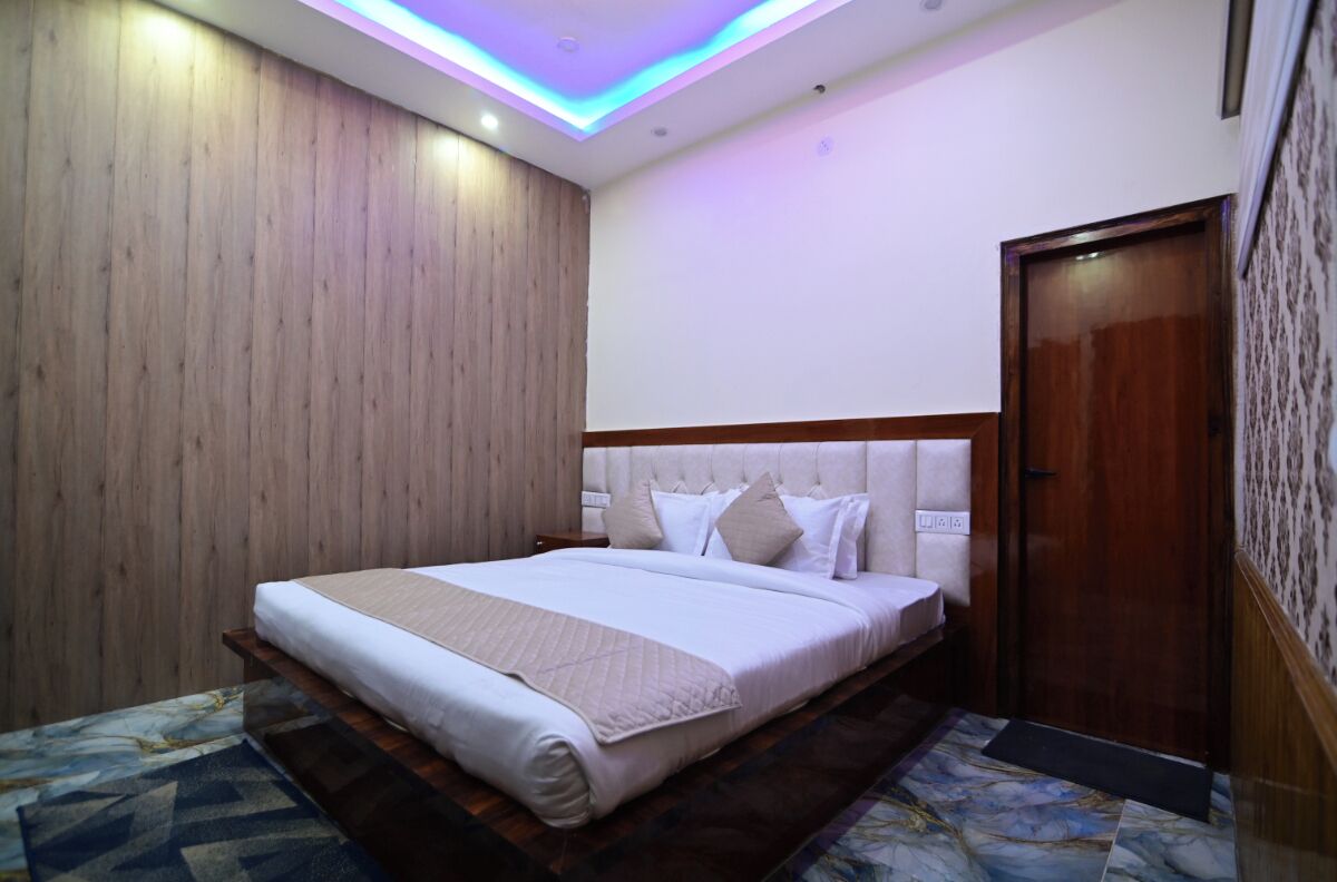 Habitación de hotel con cama, paredes de paneles de madera, puerta de madera y alfombra estampada.