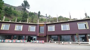 Un edificio de dos plantas con fachada oscura y numerosas ventanas.