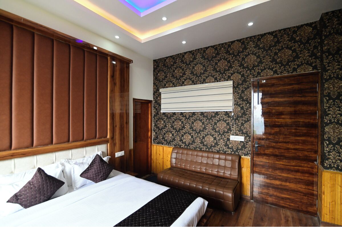 Una habitación de hotel con cama, sofá, armario de madera y pared con diseño.