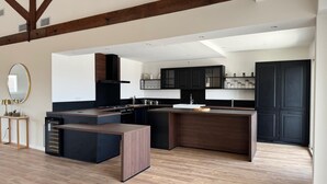 A modern kitchen with a central island, dark cabinetry, and a wooden ceiling.