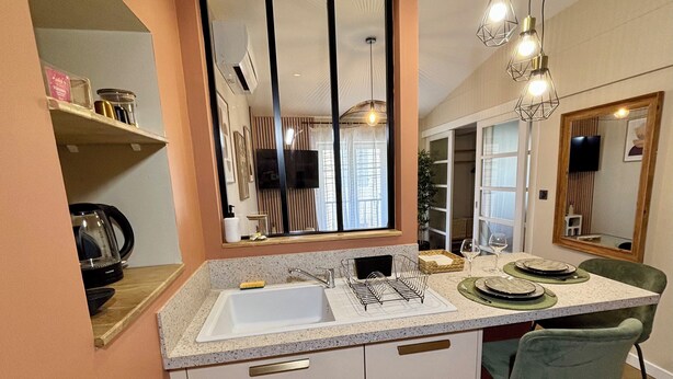 A modern kitchen with a built-in sink, a dining area with a green chair, and pendant lighting. - House + garage in the heart of ORANGE (Orange)