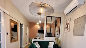 A modern living room with a green sofa, a coffee table, and a hanging light fixture. - House + garage in the heart of ORANGE (Orange)