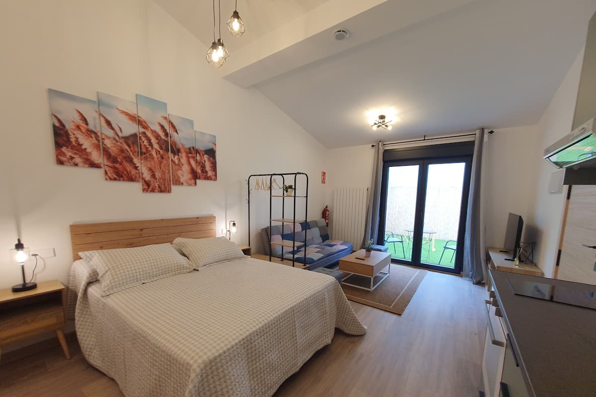 Een slaapkamer met een groot bed, een sofa, een bureau en een balkon met uitzicht.
