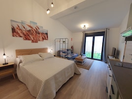 Un dormitorio con una cama grande, un sofá, un escritorio y un balcón con vistas.