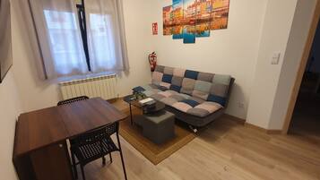 Ein Wohnzimmer mit einer Couch, einem Couchtisch, einem Esstisch und einem Sessel.