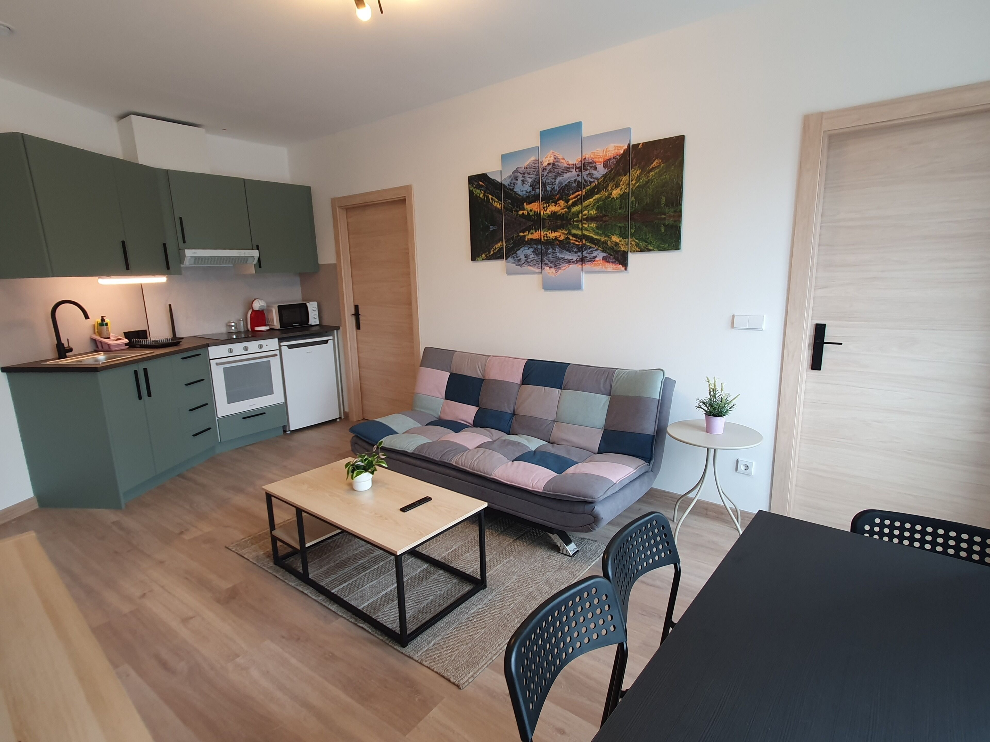 Een gezellig, compact leefruimte met een kitchenette, een bank, een salontafel en een eettafel.