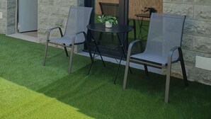 A building with a stone facade, a sliding glass door, and a small patio area with two chairs and a table. - Sella Rooms (Arriondas)