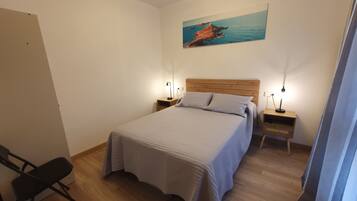 Une chambre à coucher avec un lit, deux tables de chevet, une chaise, un tableau au mur et un plancher en bois.