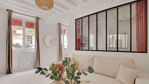 A living room with a sofa, a coffee table, and a window with curtains.