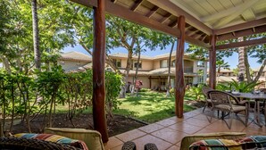 Un patio techado con mobiliario de mimbre y vista a un barrio residencial.