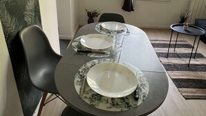A dining area with a table set for four, chairs, a window with curtains, and a plant on the windowsill. - 5-minute walk from TGV station (Châtellerault)