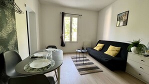 A dining area with a table set for four, a black sofa with yellow cushions, and a small side table. - 5-minute walk from TGV station (Châtellerault)