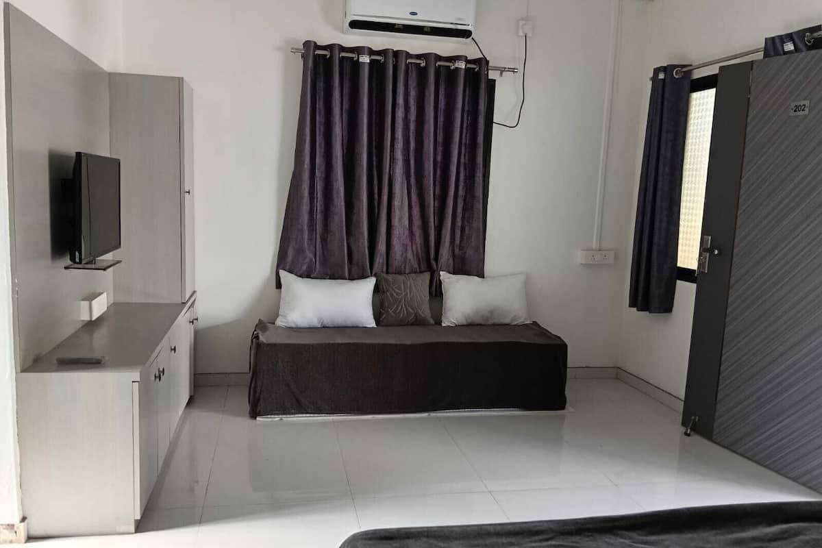 A bedroom with a bed, a TV, a wardrobe, and an air conditioning unit.