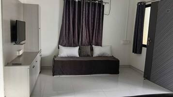 A bedroom with a bed, a TV, a wardrobe, and an air conditioning unit.