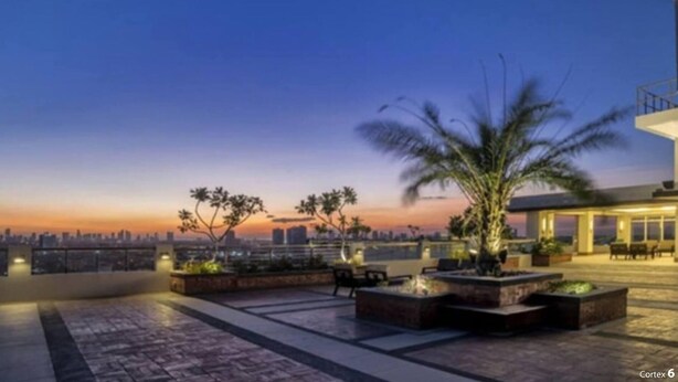 A rooftop terrace with seating areas, planters, and a city skyline view at dusk. - Room-peaceful City View Condo for Rent i (Quezon City)