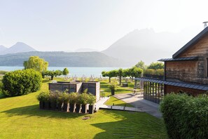 Una proprietà sul lago con una casetta di legno, un patio con posti a sedere e un prato curato.