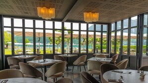 A restaurant with large windows, tables, and chairs.