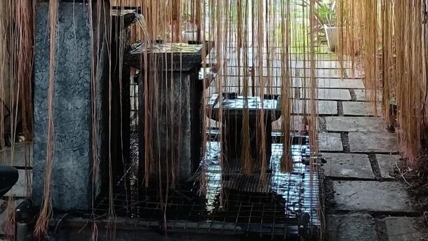 Un jardin japonais traditionnel agrémenté d’une lanterne en pierre, d’un petit bassin et d’un paravent en bambou.
