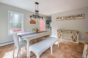 A dining area with a white table, bench, and chandelier. There is a sign on the wall that reads "NEW HAMPSHIRE LIVE FREE OR DIE". - “Big Red” @ New London/Sunapee - Overflow Unit (New London)