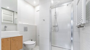A modern bathroom with a glass shower enclosure, a toilet, and a wooden vanity.