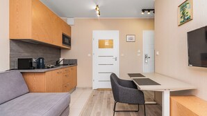 A modern kitchen with wooden cabinets, a grey sofa, and a dining table with chairs.