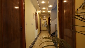 A hallway with wooden doors, a marble floor, and recessed ceiling lights. - Perfectstayz Hills Rishikesh (Rishikesh)