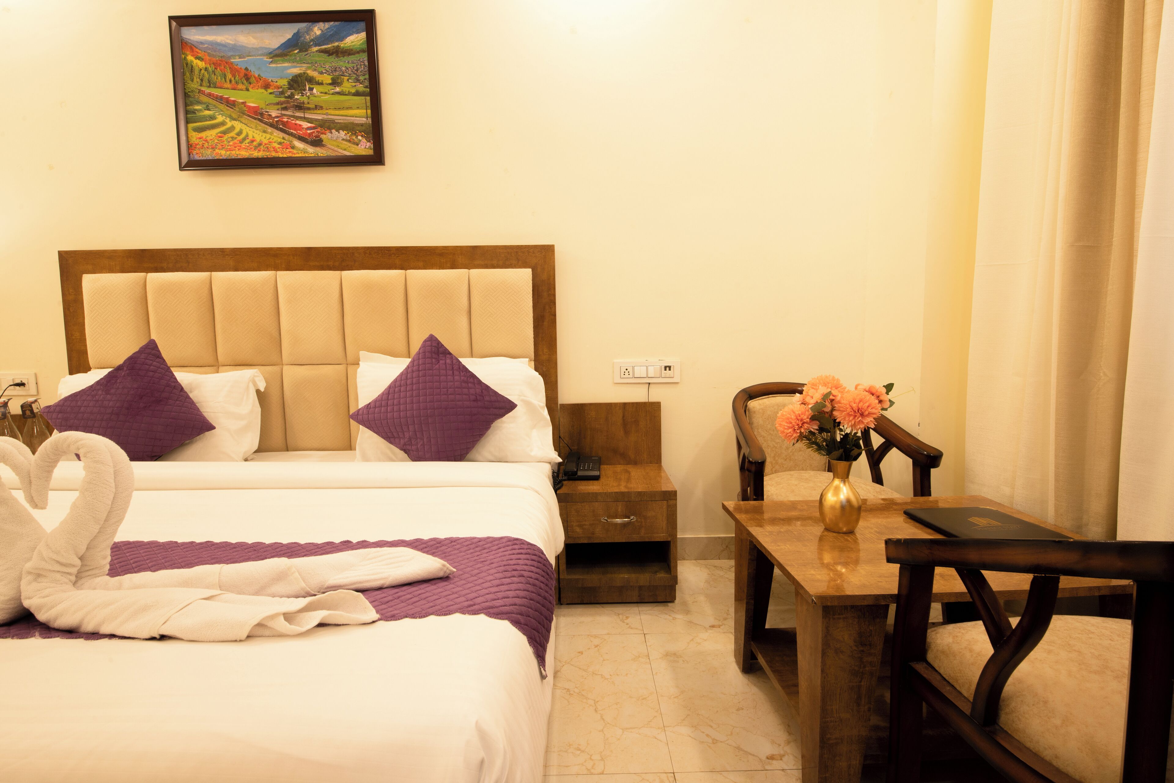 Una habitación de hotel con una cama, una mesita de noche, una mesa de madera con un florero y una silla.