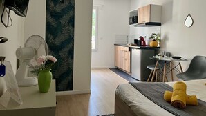 Un espace de vie moderne et compact comprenant un coin cuisine, un espace repas et une chambre.