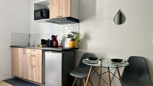 Une cuisine compacte équipée d’un four à micro-ondes encastré, d’un réfrigérateur en acier inoxydable et d’un petit coin repas comprenant deux chaises et une table.
