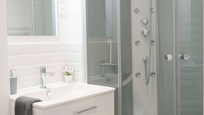 Une salle de bain moderne avec une douche à parois de verre, un meuble-lavabo blanc et un miroir au-dessus du meuble-lavabo.