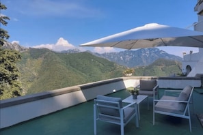 A rooftop terrace with outdoor furniture, a table, and a large umbrella. - Entire Villa (Ravello)