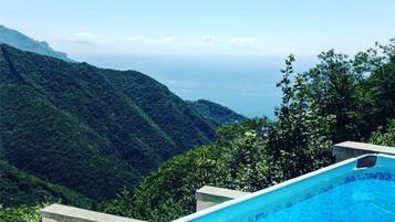 Une piscine offrant une vue sur un paysage montagneux et la mer.
