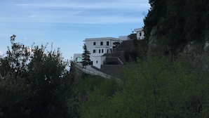 En bygning med flere etager i moderne arkitektur, beliggende på en skråning omgivet af frodig vegetation.